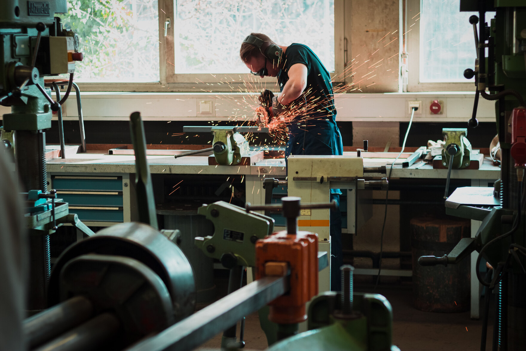 Ein Mann mit einem Winkelschleifer arbeitet in einer Werkstatt.