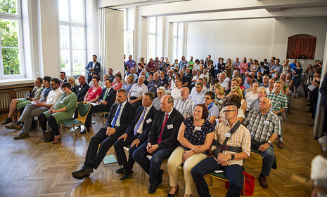 Menschen sitzen in einem großen Saal.