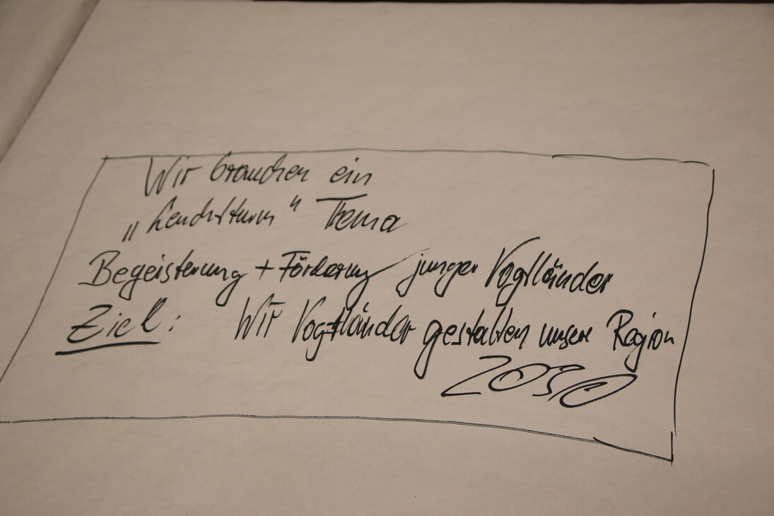 Auf einem Flipchart steht: »Wir brauche ein Leuchtturm-Thema. Begeisterung und Förderung junger Vogtländer. Ziel: Wir Vogtländer gestalten unsere Region 2030.