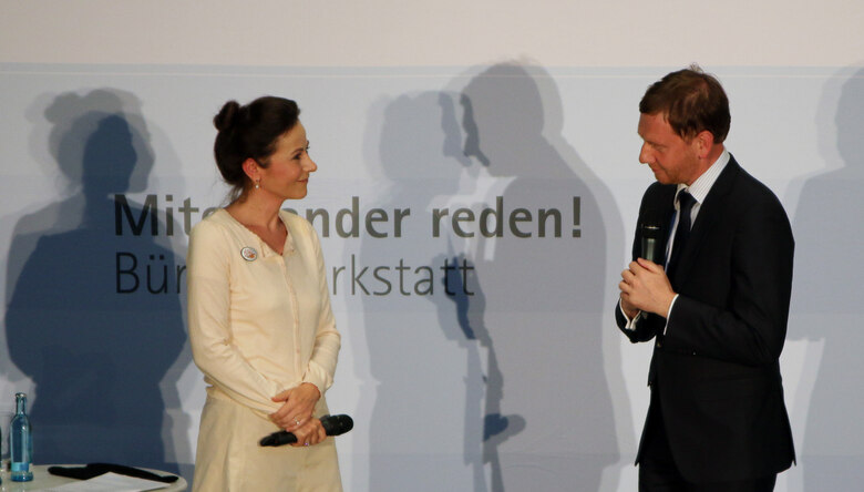 Eine Frau und ein Mann sprechen auf einer Bühne miteinander.