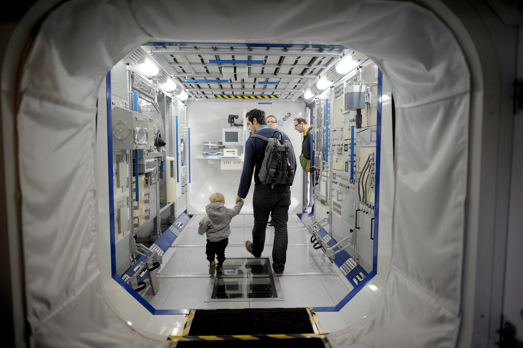 Ein Mann geht mit seinem Sohn durch eine Raumkapsel.