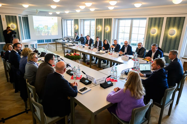 Männer und Frauen sitzen an einem Konferenztisch.