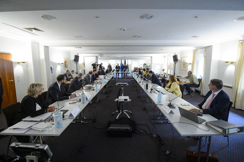 Männer und Frauen sitzen an einem Tisch in U-Form.