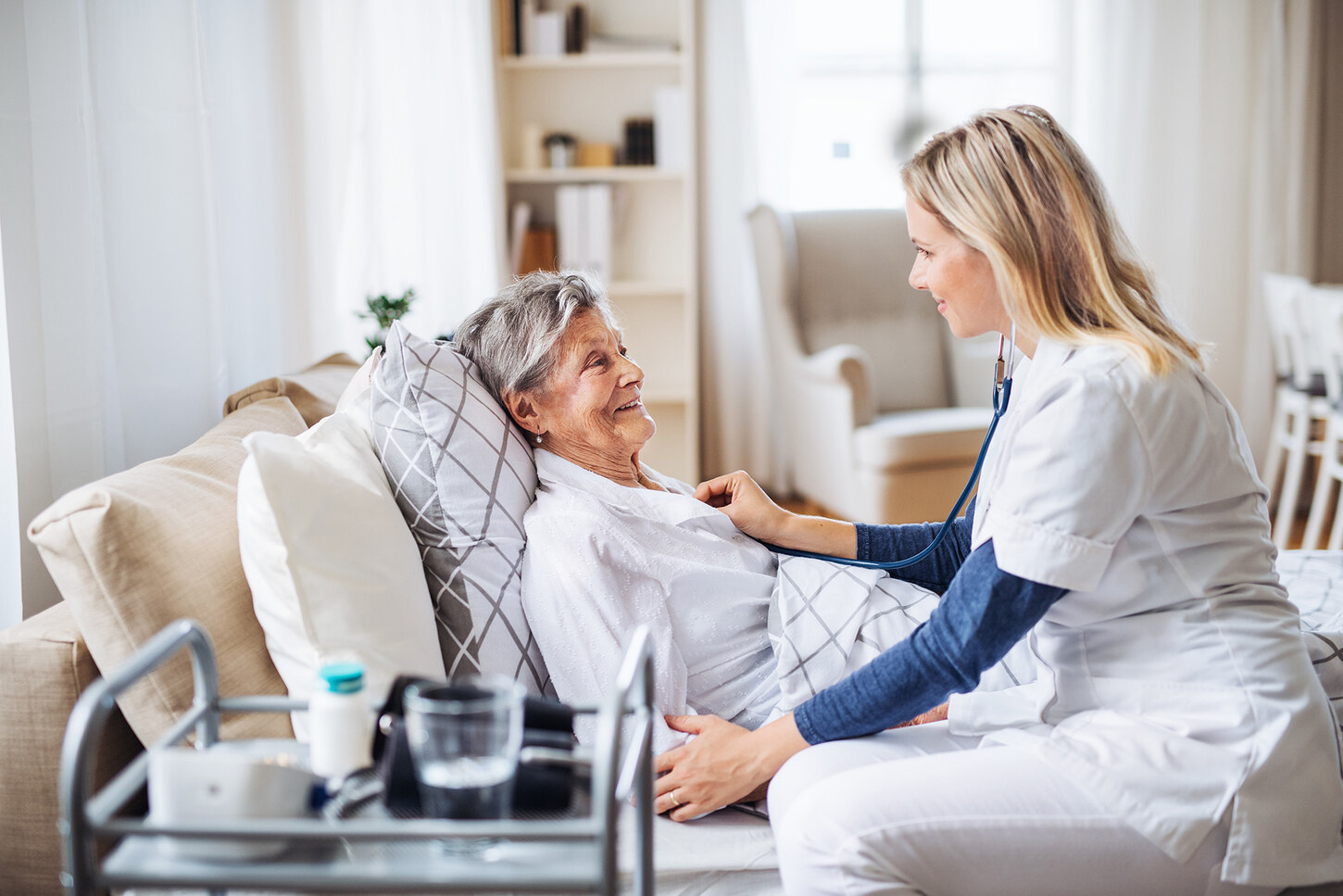 Eine Ärztin behandelt eine Patientin, die in einem Bett liegt.