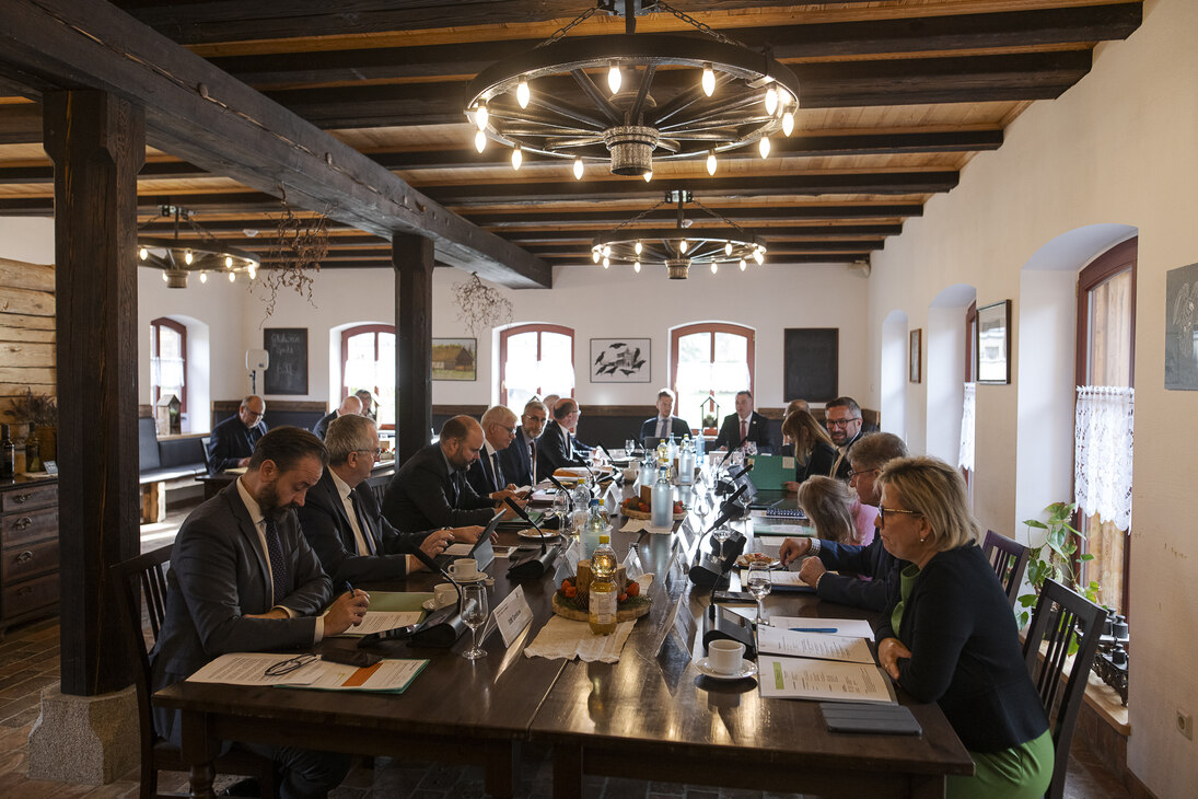 Männer und Frauen sitzen an einem Konferenztisch.