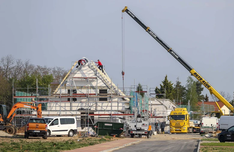 Hausbau mit Baukran in einer Einfamiliensiedlung.