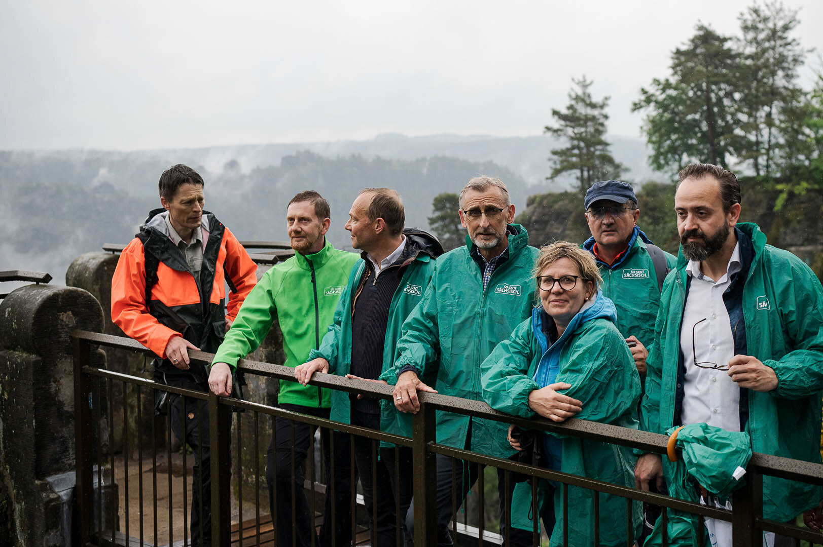 Männer und Frauen stehen auf einer steinernen Brücke.