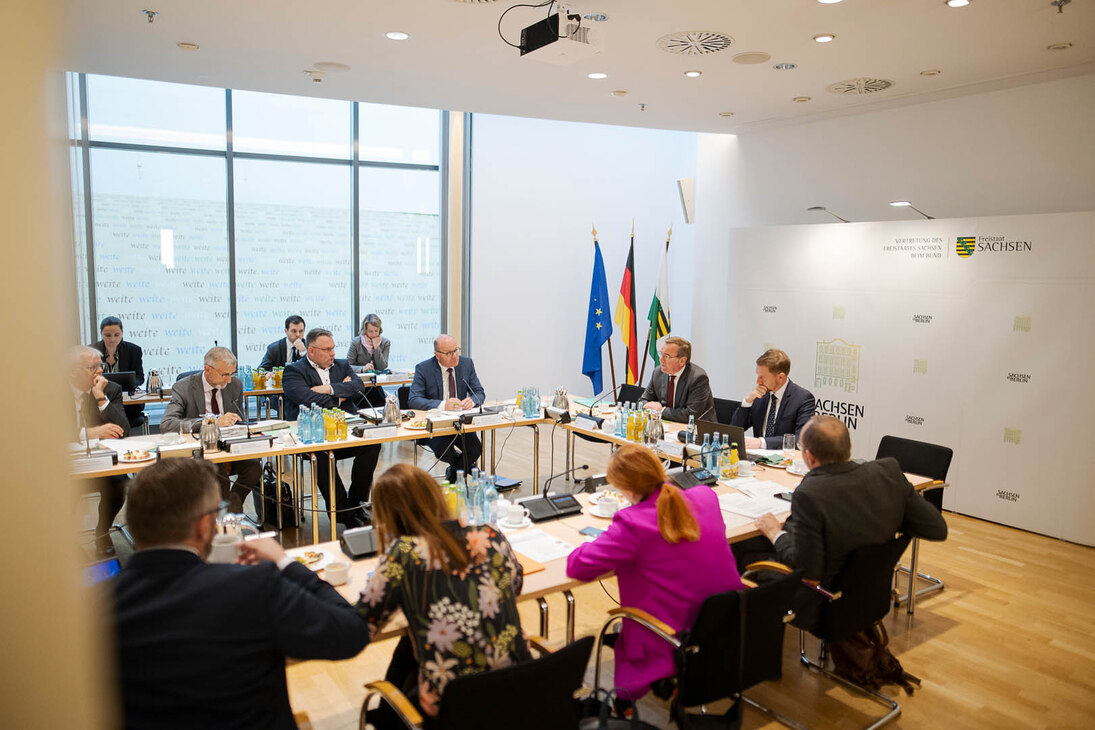 Männer und Frauen sitzen in einem Konferenzsaal.