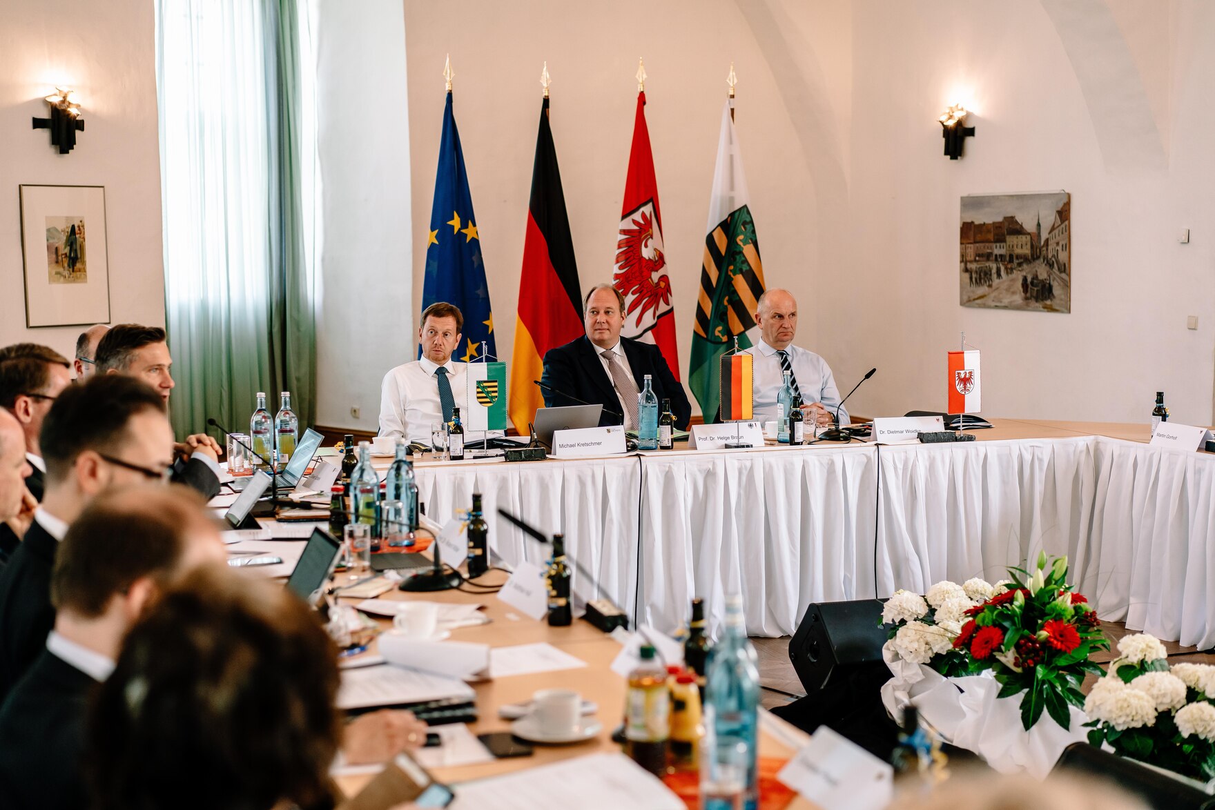 Männer und Frauen sitzen an einer Tafel.