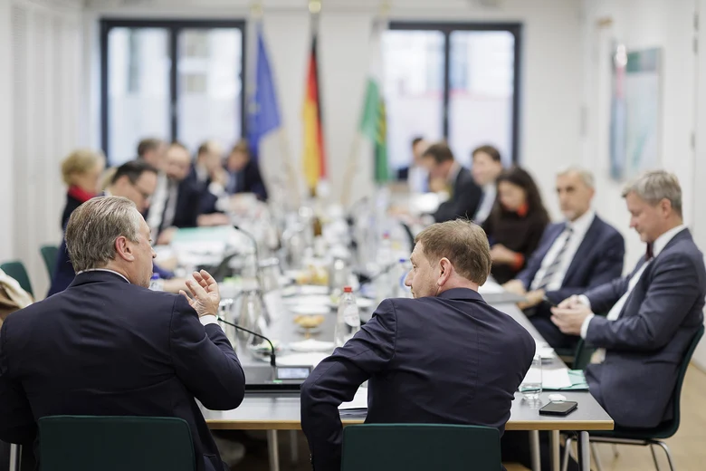 Männer und Frauen sitzen an einem Tisch.