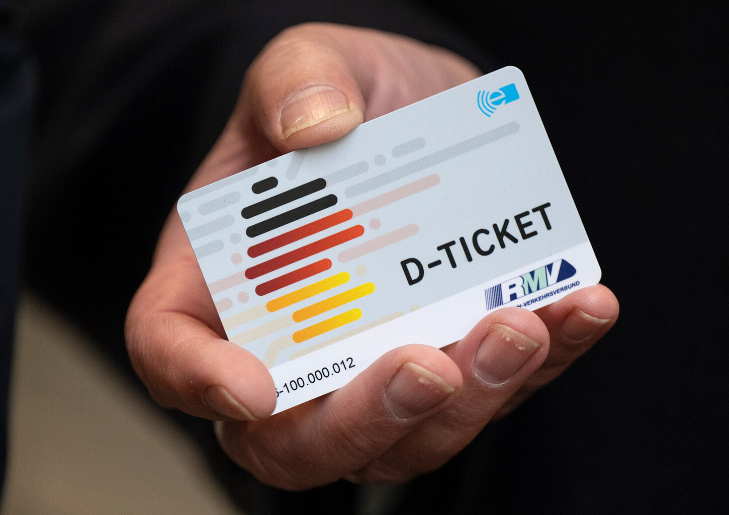 Eine Hand hält ein Deutschlandticket in Form einer Chipkarte.