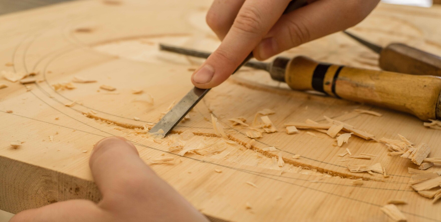 Ein Tischler arbeitet mit einem Hobel auf einem Holzstück.
