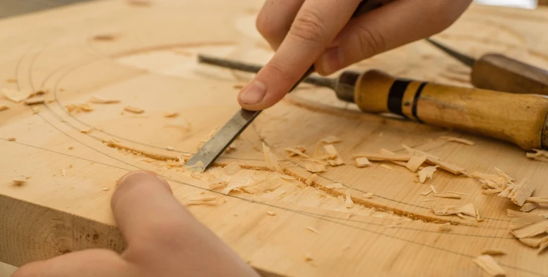 Ein Tischler arbeitet mit einem Hobel auf einem Holzstück.