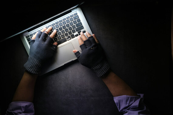 Ein Mann bedient einen Laptop mit Handschuhen.