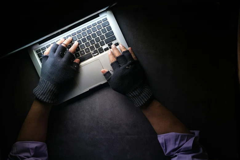 Ein Mann bedient einen Laptop mit Handschuhen.