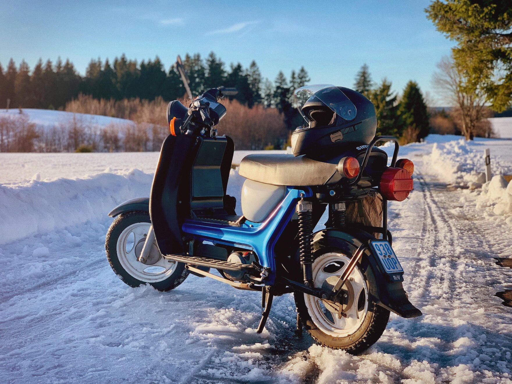 Ein Moped steht am Rande eines schneebedeckten Feldes.