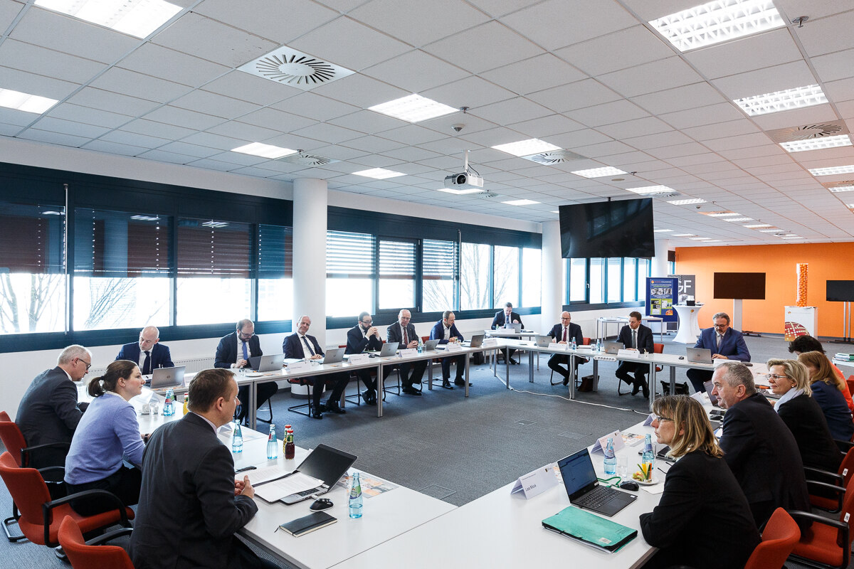 Männer und Frauen halten in einem modern eingerichteten Saal ein Meeting ab.