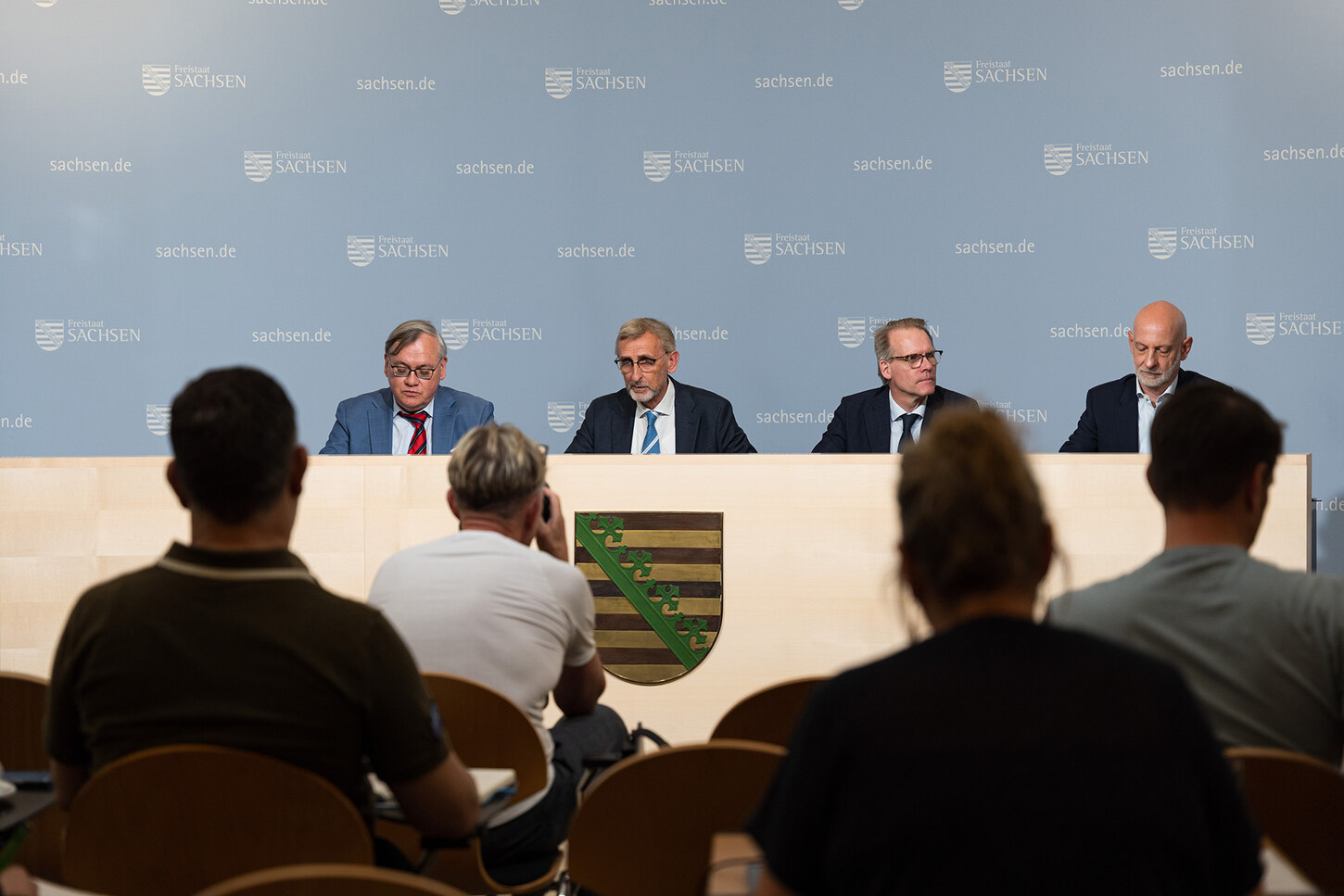 Männer sitzen auf einem Podium.