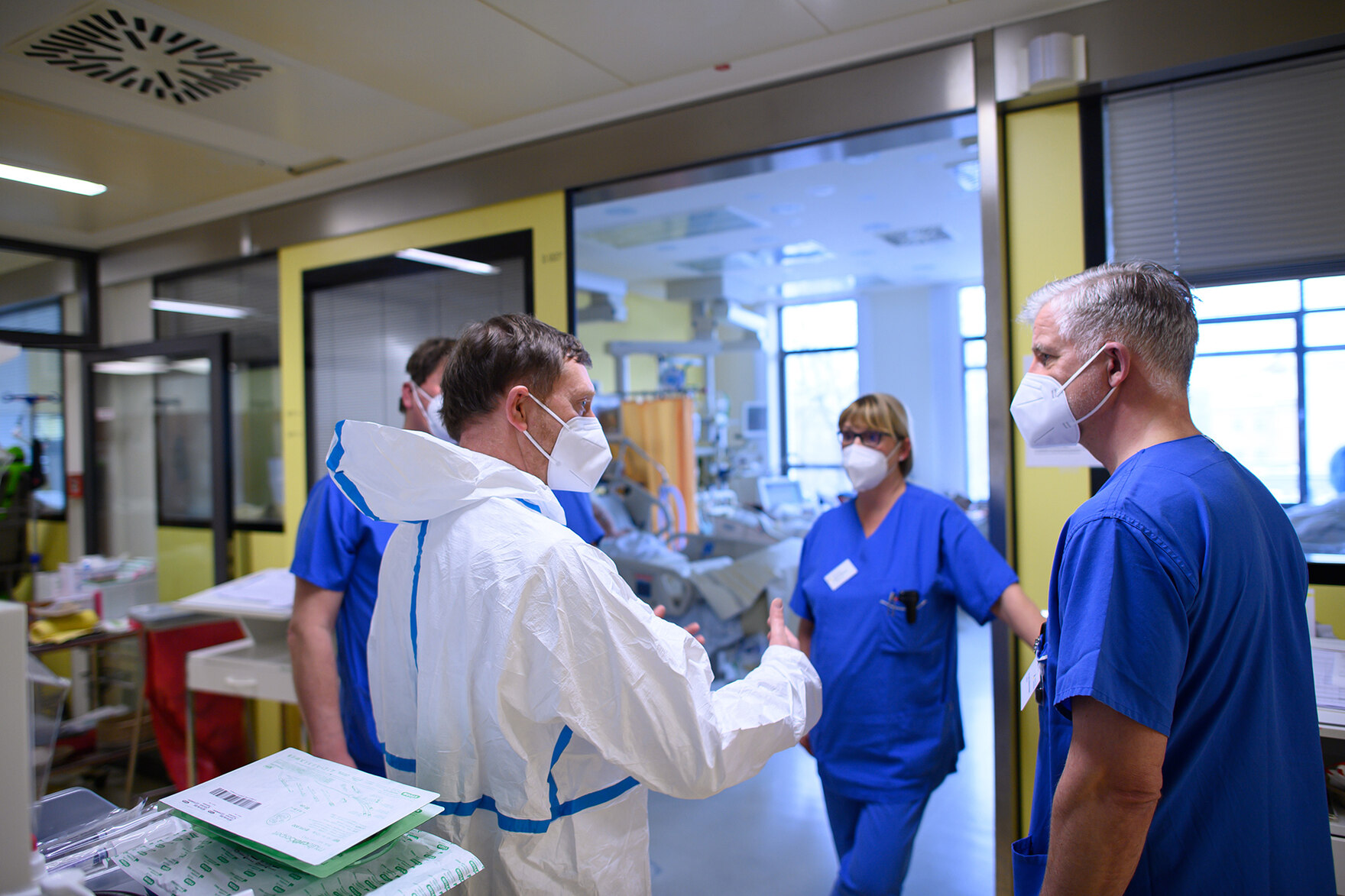 Menschen stehen in Schutzanzügen in einer Klinik.