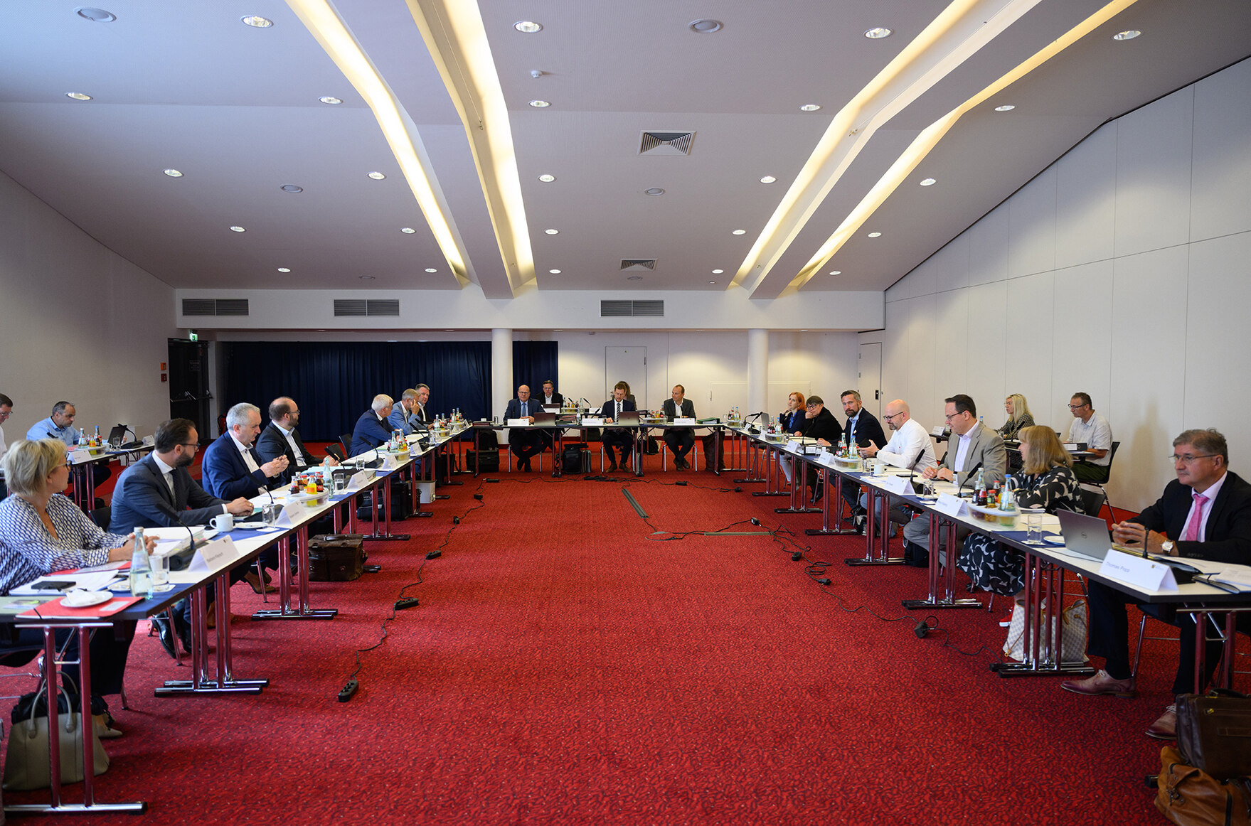 Männer und Frauen sitzen in einem Konferenzraum und tagen.