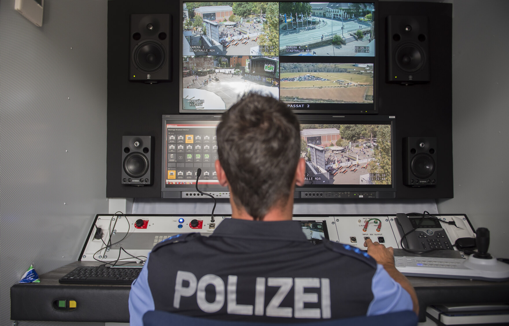 Ein Polizist sitzt vor einer Monitorwand.