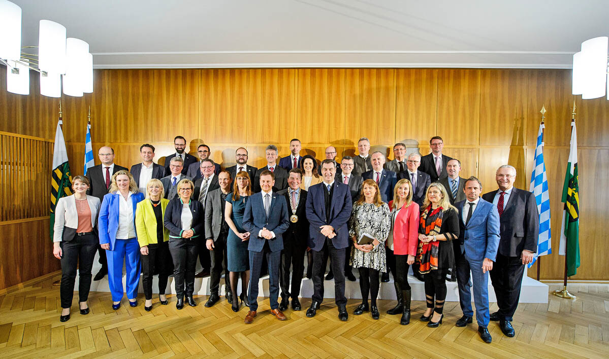 Männer und Frauen stehen in einem großen Saal.