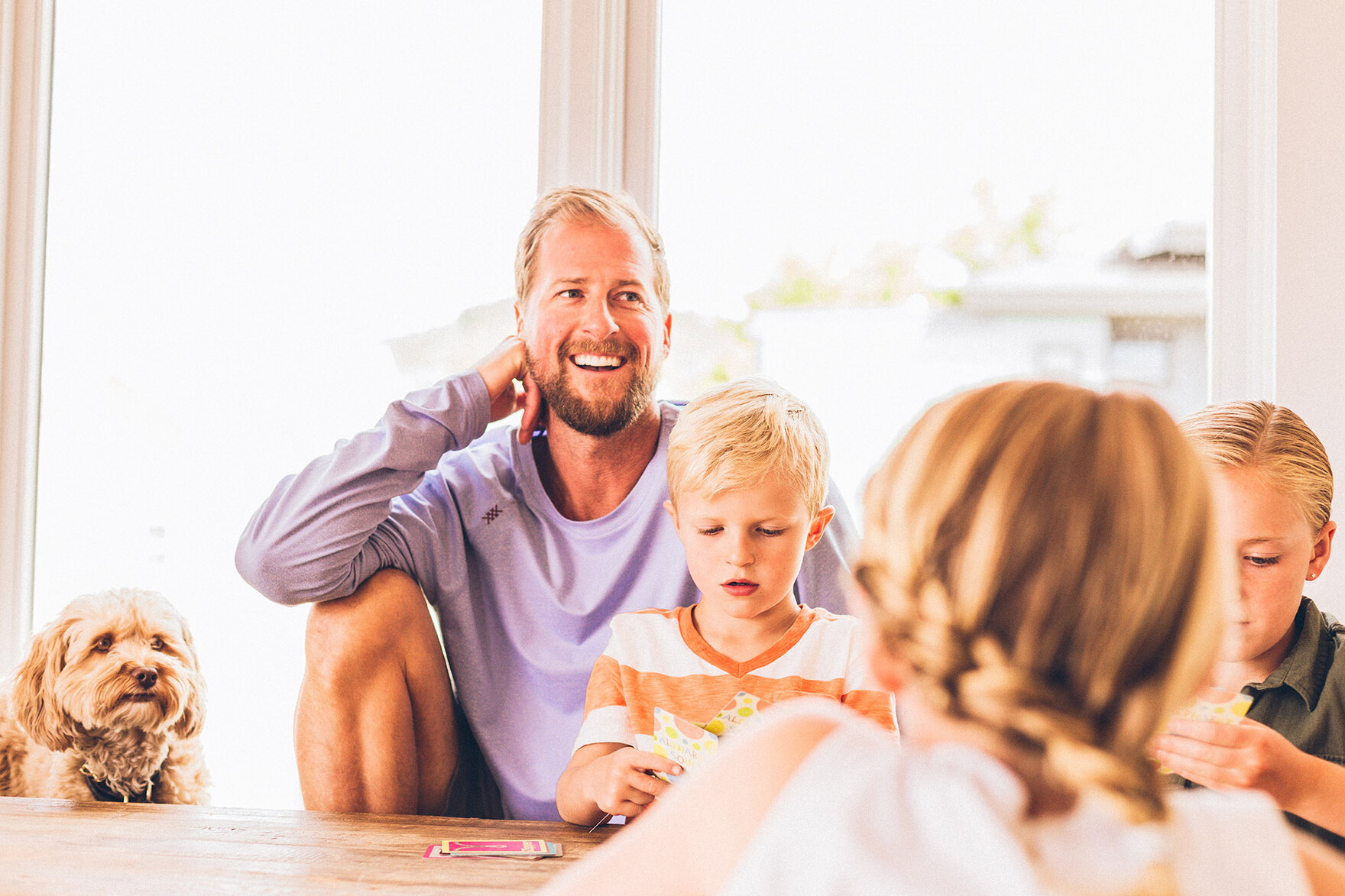 Ein Familienvater sitzt mit sienen Kindern an einem Tisch.